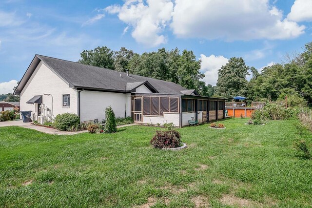 rear view of property featuring a yard, brick siding, and a sunroom