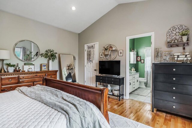 bedroom with lofted ceiling, light wood-style flooring, and ensuite bathroom