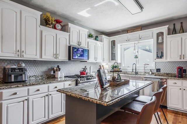 kitchen with dark stone counters, stainless steel appliances, glass insert cabinets, and a center island