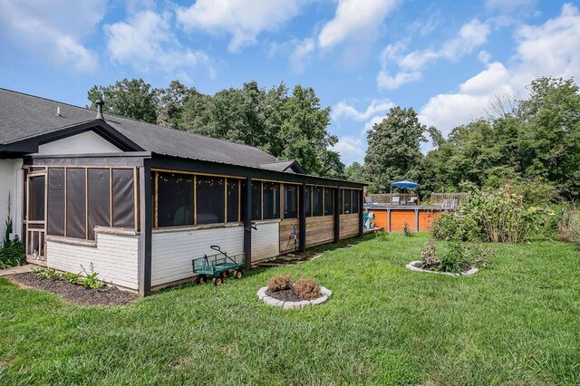 exterior space featuring a sunroom, a pool, and a lawn