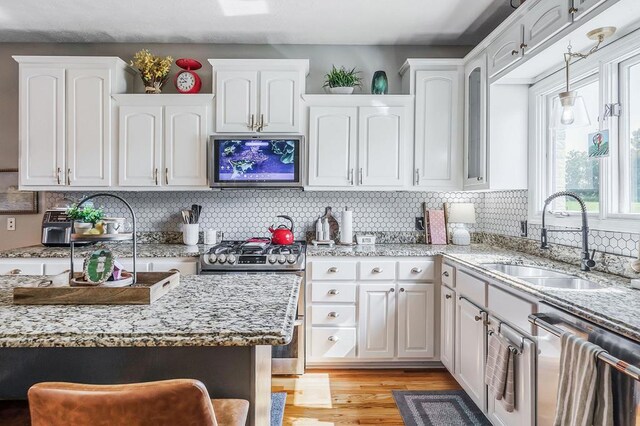 kitchen featuring appliances with stainless steel finishes, a sink, light wood-style floors, and white cabinets