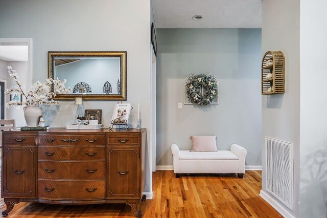 living area with light wood-style flooring, visible vents, and baseboards