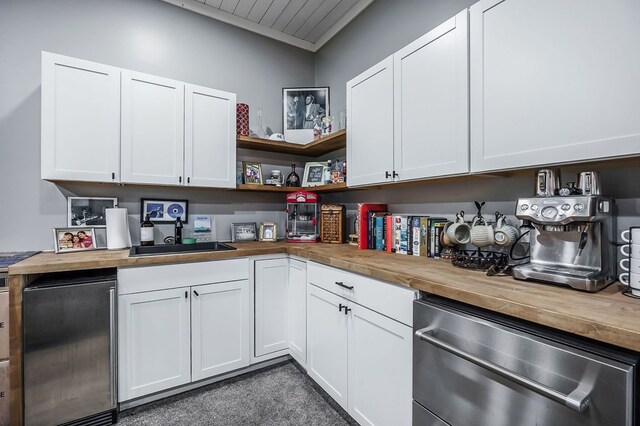 kitchen featuring appliances with stainless steel finishes, white cabinetry, wooden counters, and open shelves