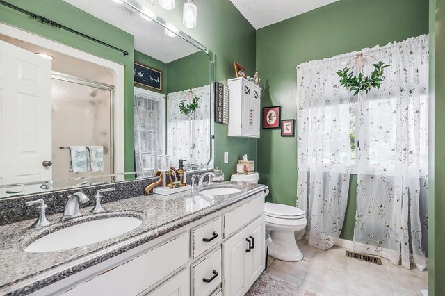 full bathroom featuring double vanity, a shower stall, a sink, and tile patterned floors