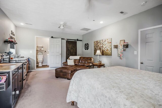 bedroom with light carpet, a barn door, a sink, and visible vents