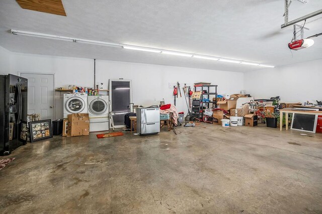 garage with a workshop area, washing machine and clothes dryer, freestanding refrigerator, and a garage door opener