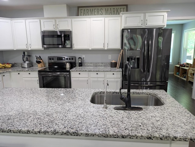 3569 Dry Mill Creek Rd, Hilham, TN 38568 - kitchen with appliances with stainless steel finishes, white cabinetry, light stone counters, and wood finished floors