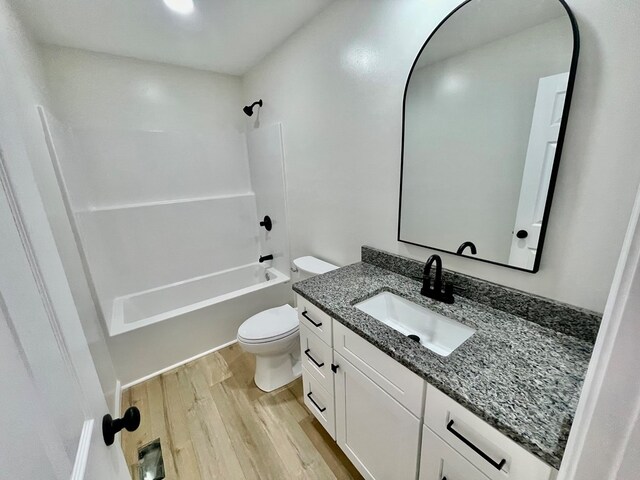 bathroom featuring toilet, washtub / shower combination, wood finished floors, and vanity