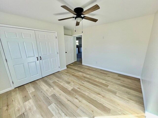 unfurnished bedroom featuring light wood-type flooring, ceiling fan, baseboards, and a closet