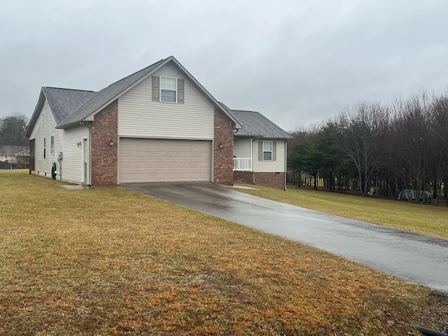 view of front facade with a garage, aphalt driveway, a front yard, and brick siding