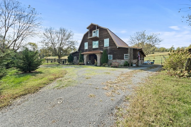 view of front of property with a barn, fence, driveway, and a gambrel roof