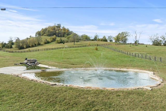 exterior space featuring fence, a lawn, and a rural view