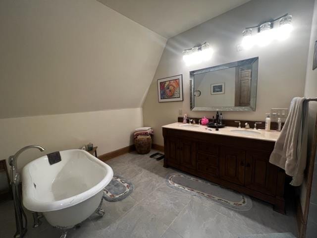 bathroom featuring lofted ceiling, a freestanding tub, a sink, baseboards, and double vanity