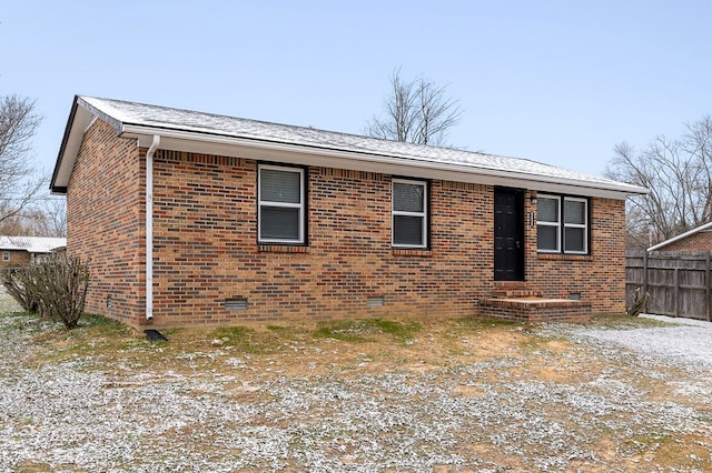 view of front of home featuring brick siding, crawl space, and fence