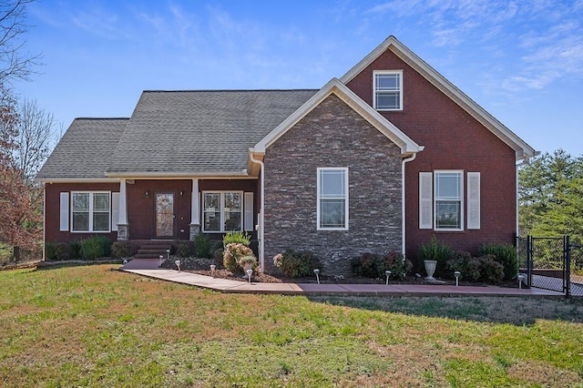 craftsman inspired home with a shingled roof, fence, a front lawn, and brick siding