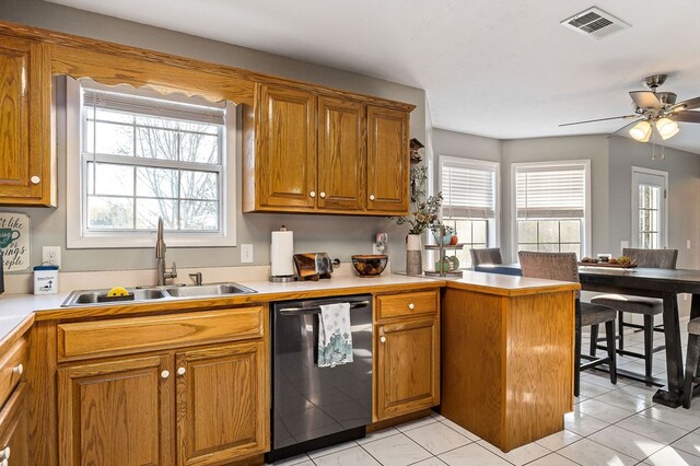 kitchen with brown cabinets, light countertops, dishwasher, and a sink