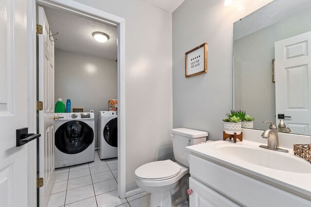 bathroom featuring washing machine and dryer, toilet, vanity, and a textured ceiling