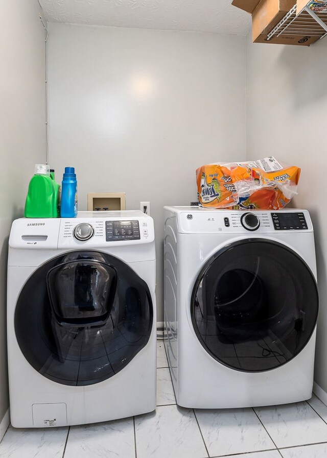 laundry room featuring marble finish floor, laundry area, a textured ceiling, and washing machine and clothes dryer