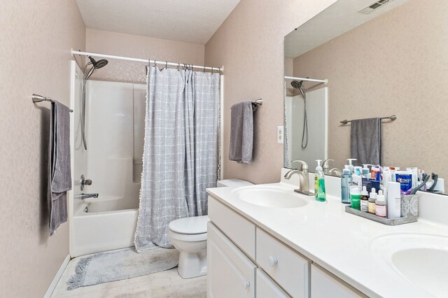 full bath with double vanity, toilet, shower / bath combo, a sink, and a textured ceiling