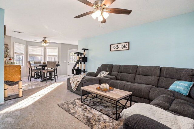 living room featuring a ceiling fan, light colored carpet, visible vents, and light tile patterned floors