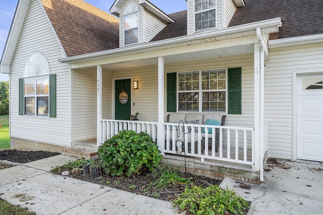 view of exterior entry featuring a shingled roof and a porch