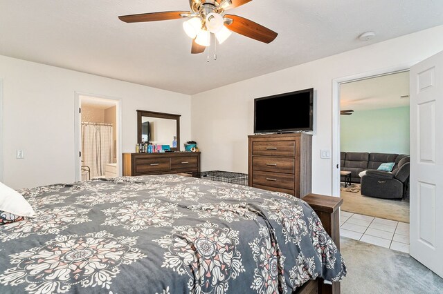 bedroom with light carpet, light tile patterned flooring, ensuite bath, and a ceiling fan