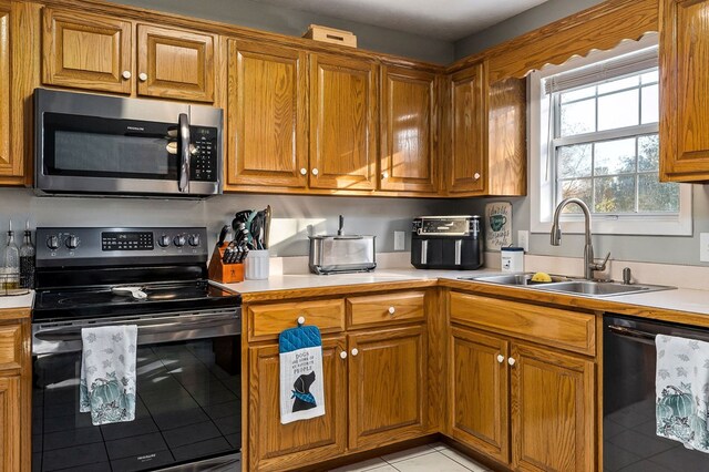 kitchen with brown cabinets, light countertops, a sink, and black appliances