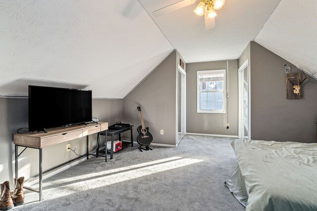 bedroom with ceiling fan, a textured ceiling, lofted ceiling, light colored carpet, and baseboards