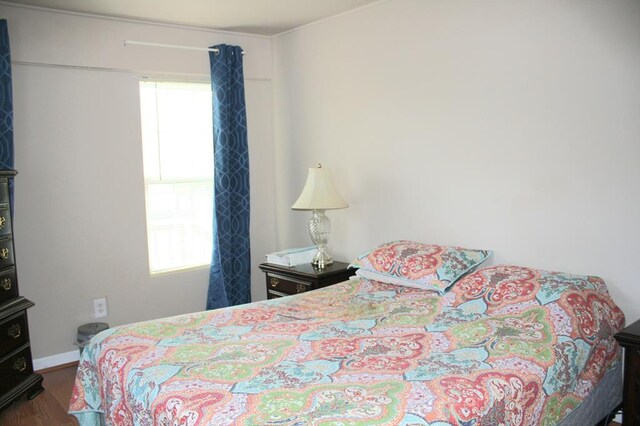 bedroom with multiple windows, dark wood finished floors, and baseboards