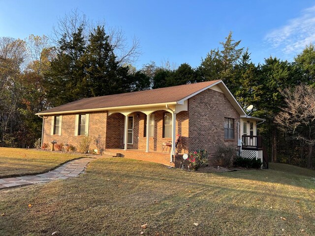 single story home featuring a porch, a front yard, and brick siding