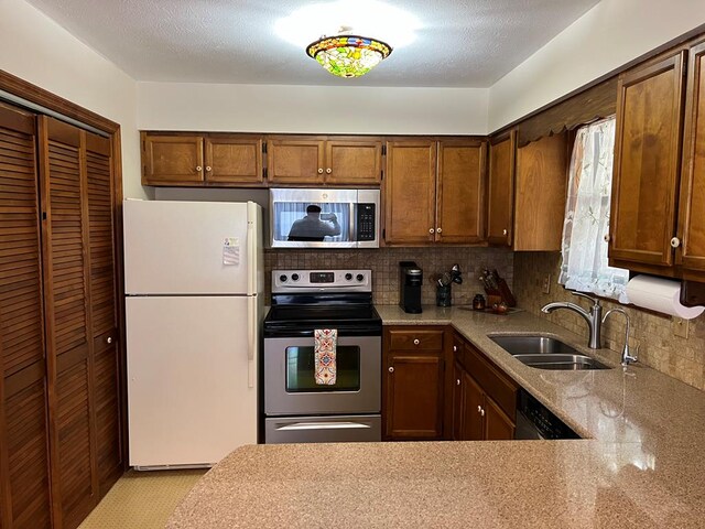 kitchen featuring appliances with stainless steel finishes, a sink, backsplash, and a textured ceiling