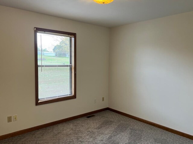 carpeted empty room with visible vents and baseboards