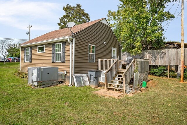 back of property with fence, a lawn, stairway, and central AC unit