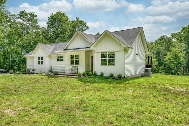 view of front facade featuring roof with shingles, a front lawn, board and batten siding, and central air condition unit