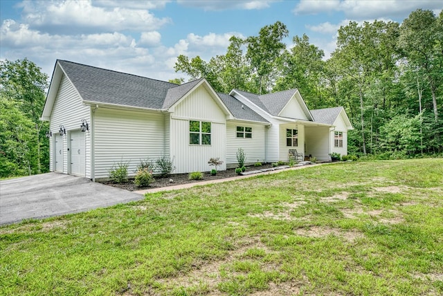 view of front of home with driveway, a front lawn, an attached garage, and a shingled roof