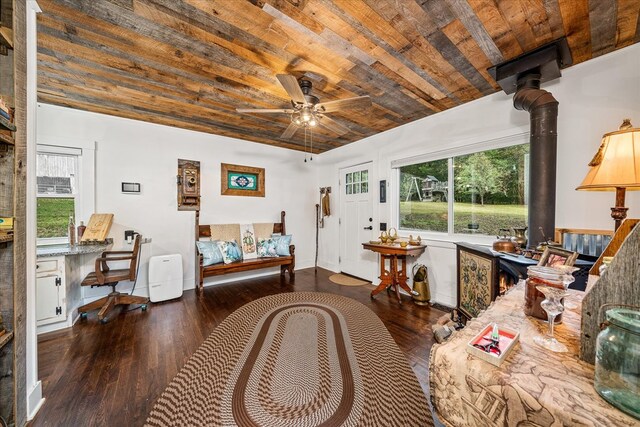 interior space with wood ceiling, baseboards, dark wood finished floors, and a wood stove