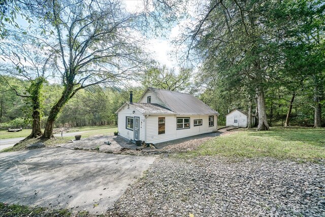 view of front of property with metal roof, driveway, and a front lawn