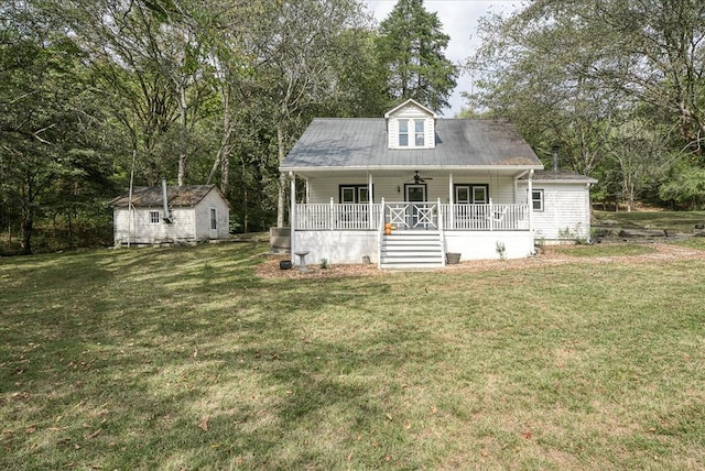 cape cod home with a porch, a front yard, and an outdoor structure