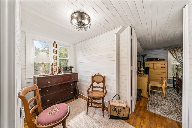 living area with wooden ceiling, dark wood-style floors, and wooden walls