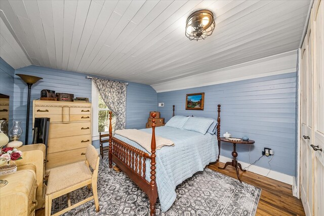 bedroom with lofted ceiling, wood walls, wood ceiling, and dark wood-style flooring