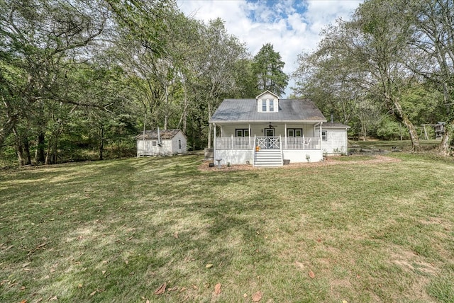 new england style home featuring covered porch, a front lawn, an outbuilding, and a storage unit