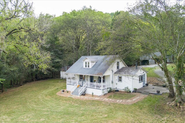 view of front of home with covered porch, metal roof, a front lawn, and stairway