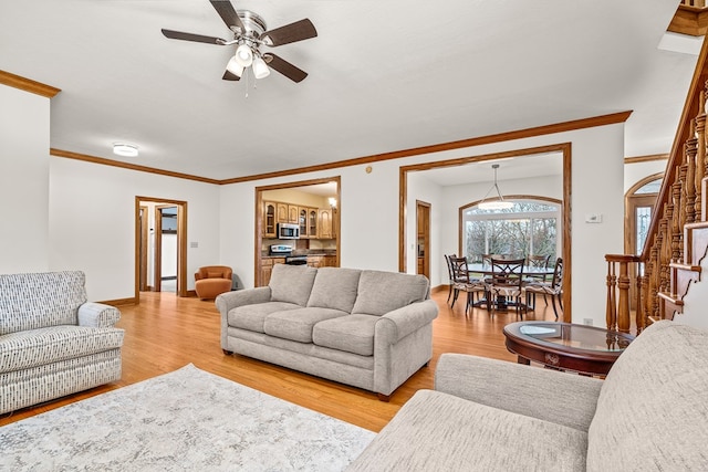 living area featuring crown molding, stairs, baseboards, and wood finished floors