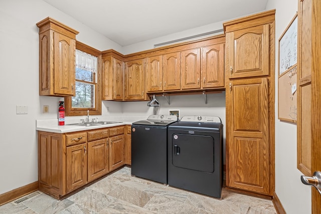 laundry room with washer and clothes dryer, visible vents, cabinet space, a sink, and baseboards