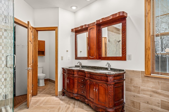 full bathroom with double vanity, a stall shower, a sink, and toilet