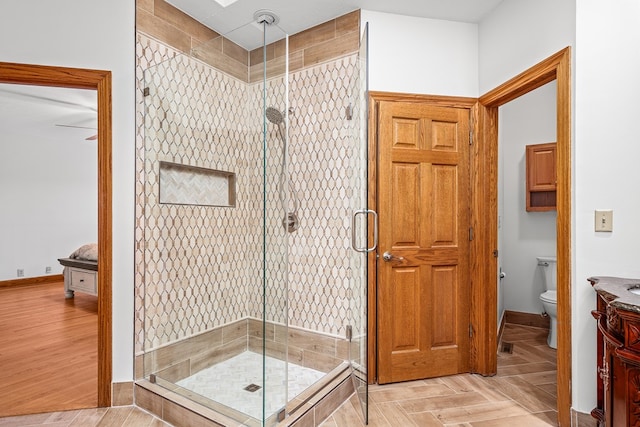 bathroom with a stall shower, baseboards, toilet, parquet floors, and vanity