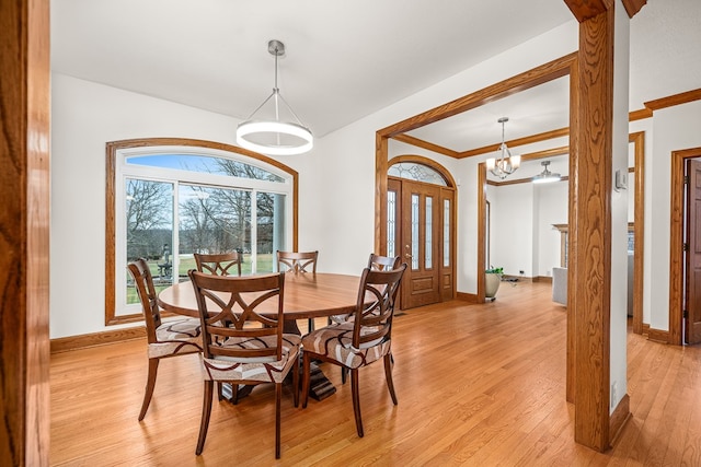 dining area with baseboards, ornamental molding, an inviting chandelier, and light wood-style floors