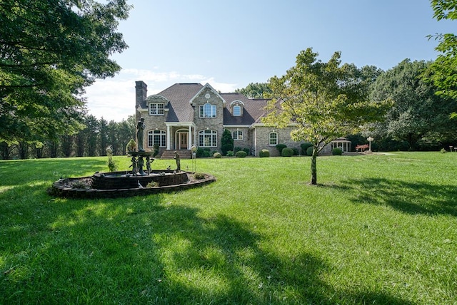 view of front facade with a front yard, stone siding, and a chimney