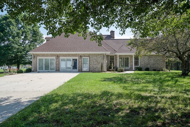 view of front of home featuring a front yard, brick siding, a chimney, and roof with shingles