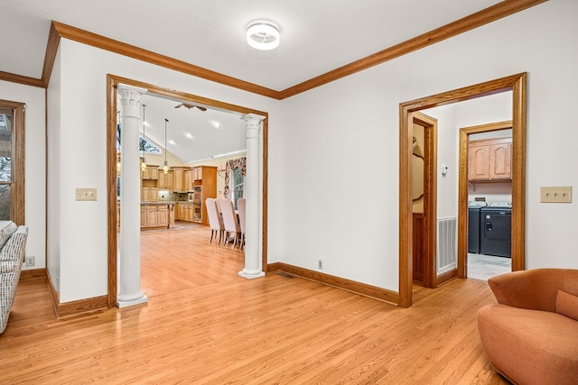 interior space featuring baseboards, light wood-style floors, ornamental molding, independent washer and dryer, and ornate columns